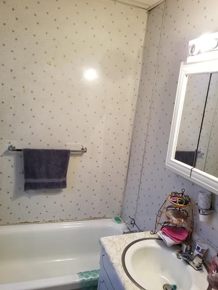 The old bathroom before the remodel, with dated wall covering and fixtures