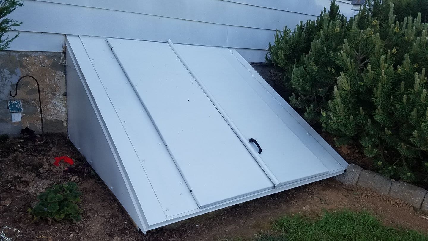 New white steel bulkhead cellar door against a house foundation