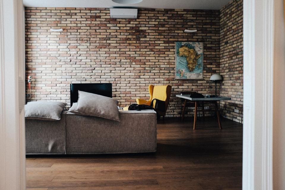 Finished lower-level living room with a brick wall and sofa