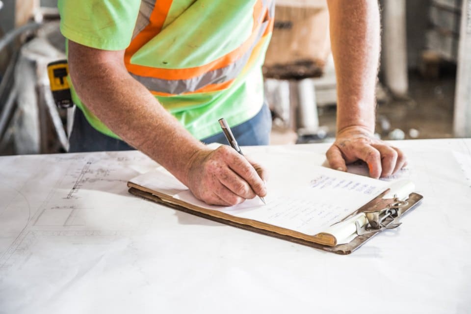 A contractor writing on a clipboard at a job site