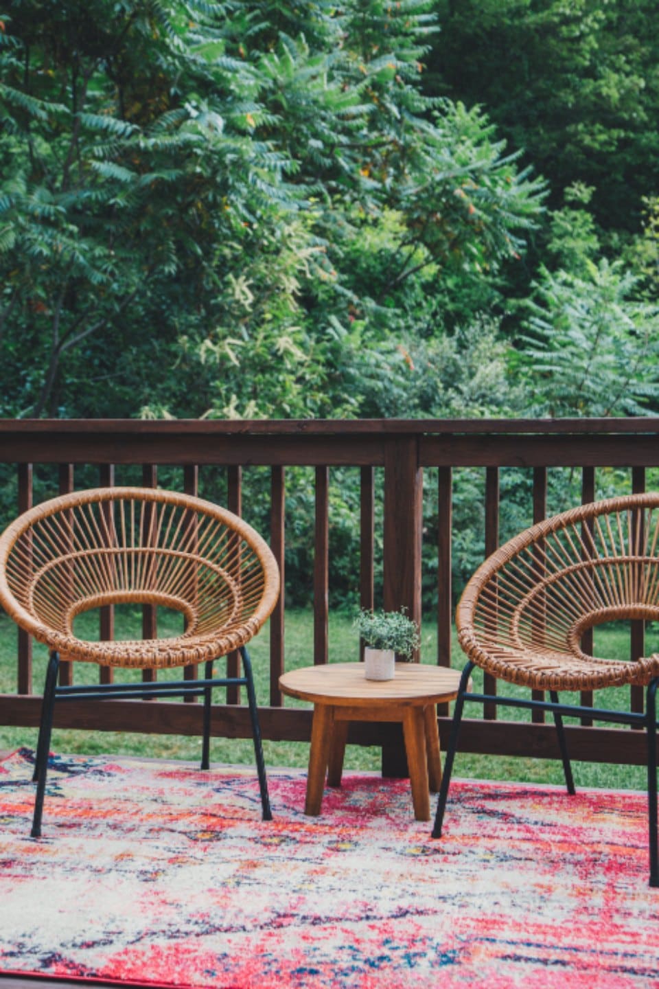 Composite deck with wicker chairs and a wood railing overlooking a yard