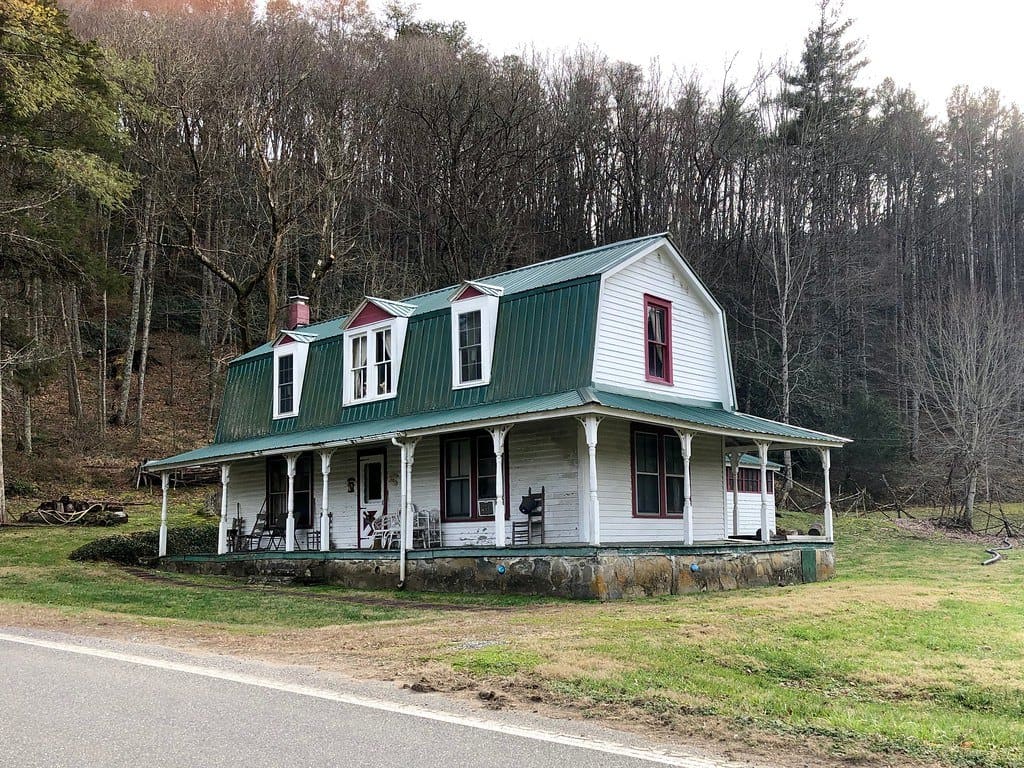 White farmhouse with a green metal roof and front porch