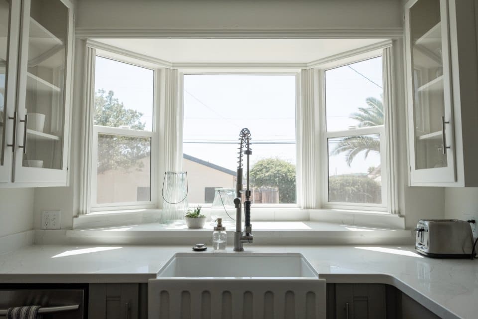 Kitchen sink under a window with white cabinets
