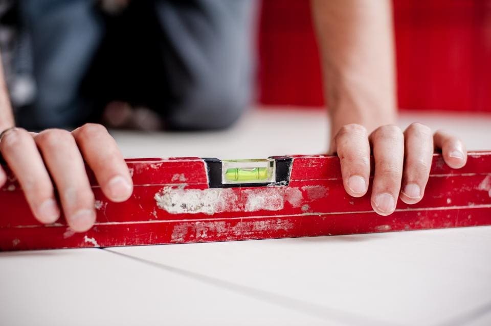 Hands holding a red level on a surface