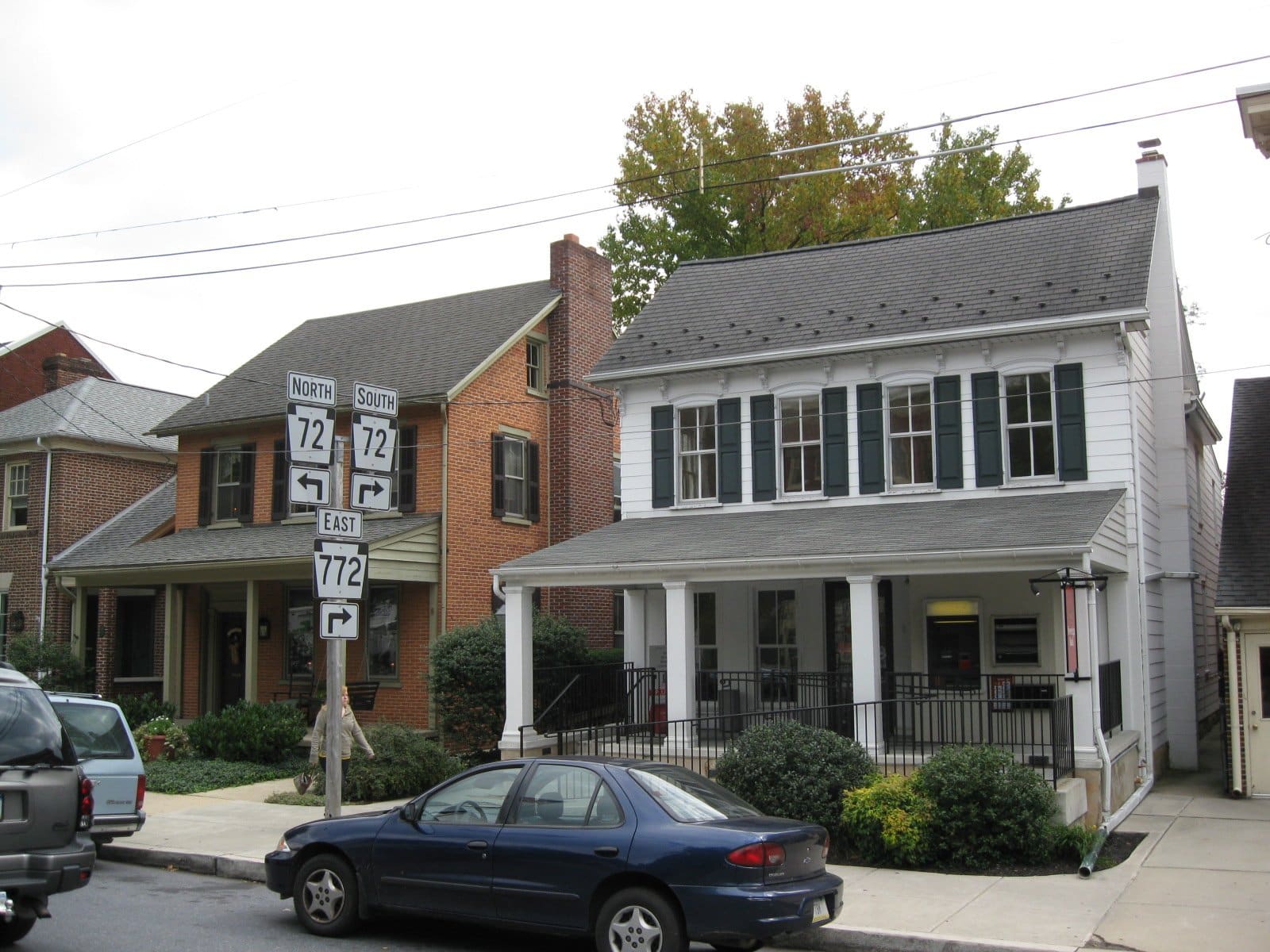 A brick home with a white porch on a street in Manheim, Pennsylvania